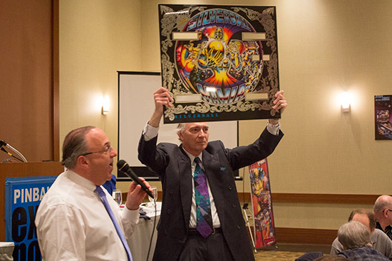 Fred Young shows the next auction item - a Silverball Mania backglass