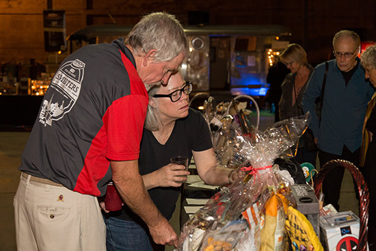 Volunteer couple John and Stephanie Kimball check out the silent auction goodies