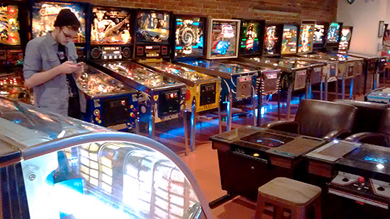 Pinballs along the left wall with cocktail videos in the centre